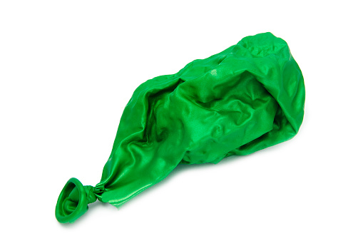 Deflated and shrivelled green balloon lying on its side