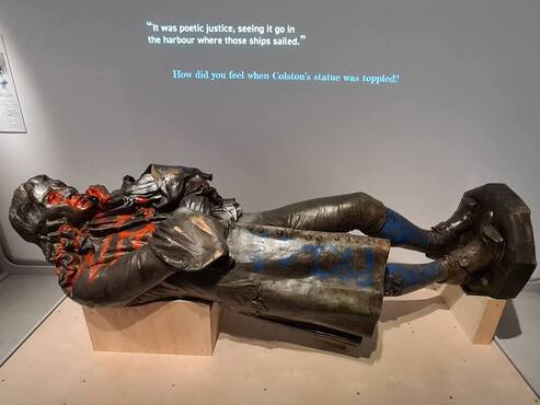 Toppled statue of Edward Colston, covered in graffiti and lying horizontal on display in the M Shed Museum in Bristol