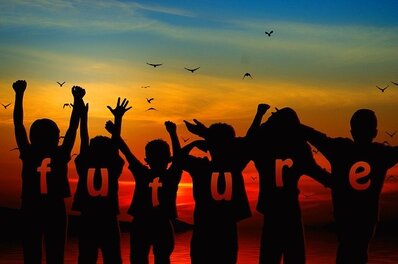 A silhouette of the back of a group of children looking towards a bright sunrise, with the word FUTURE written across their backs