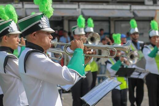 Person with green feathered hat playing a trumpet fanfare