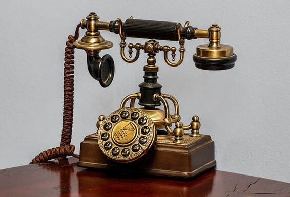 A very old-fashioned brass telephone, with a very large speaker and a circual mechanical dial