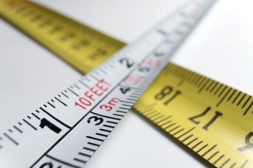 Close-up photo of two tape measures - a white one crossing over the top of a yellow one